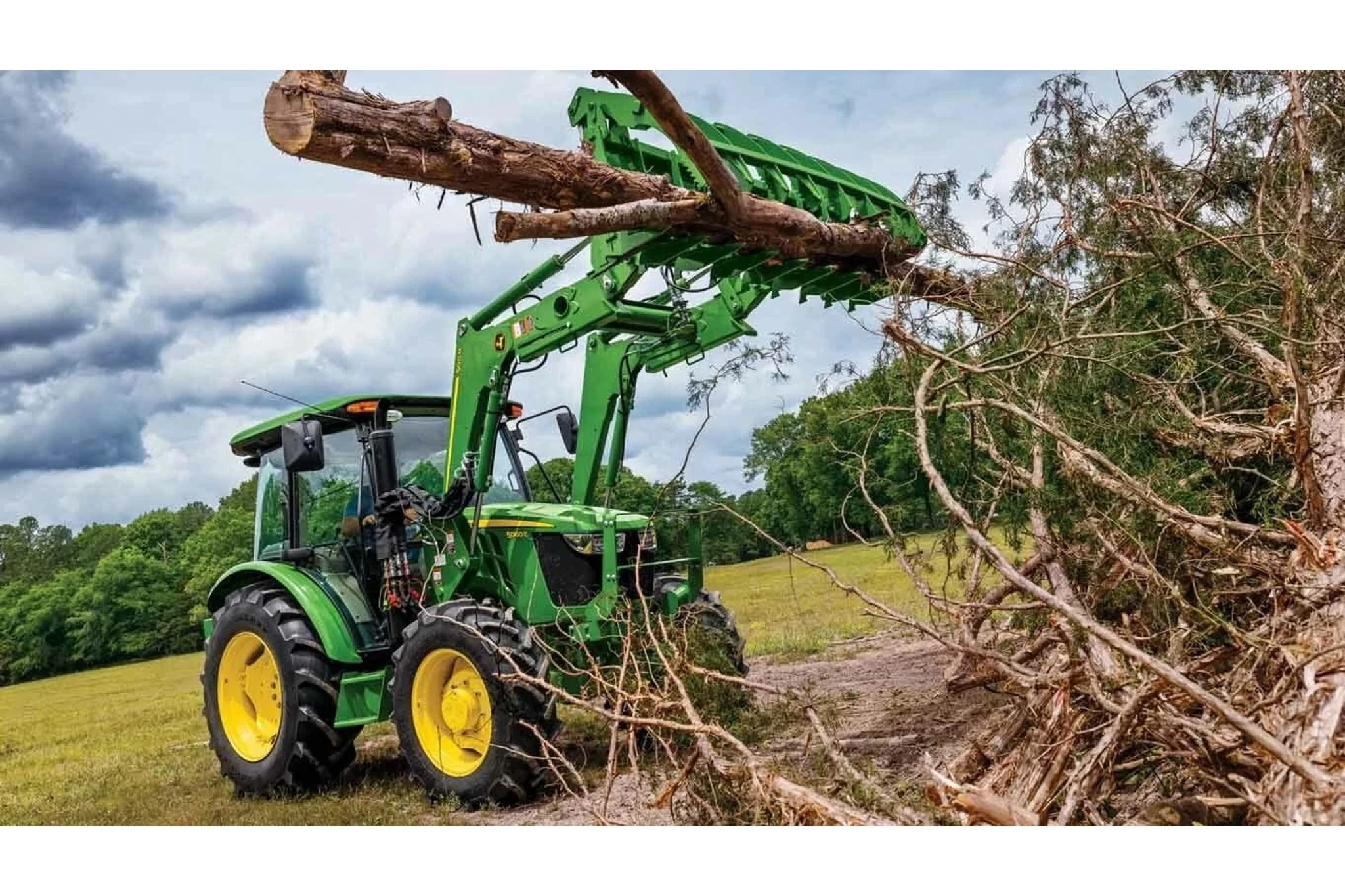 500M Loader lifting heavy tree branch from large pile of branches