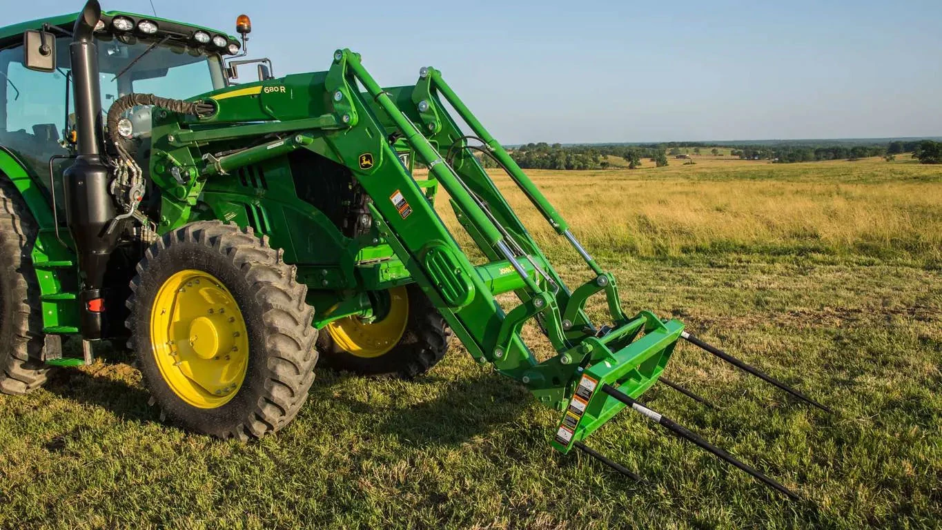 680R Loader with bale spear on a tractor driving through a field