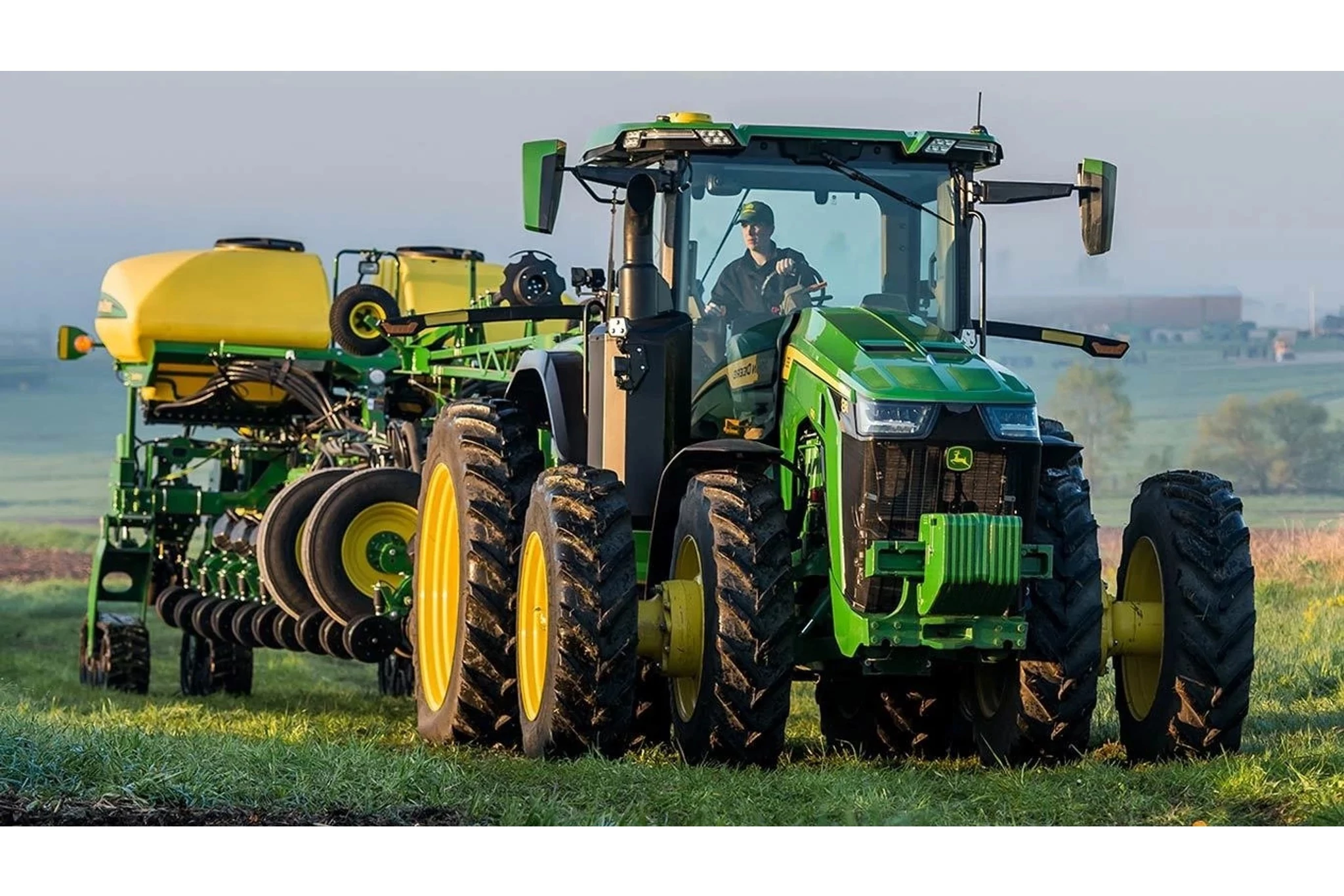 8R 310 Tractor in a grassy field with a sprayer attachment