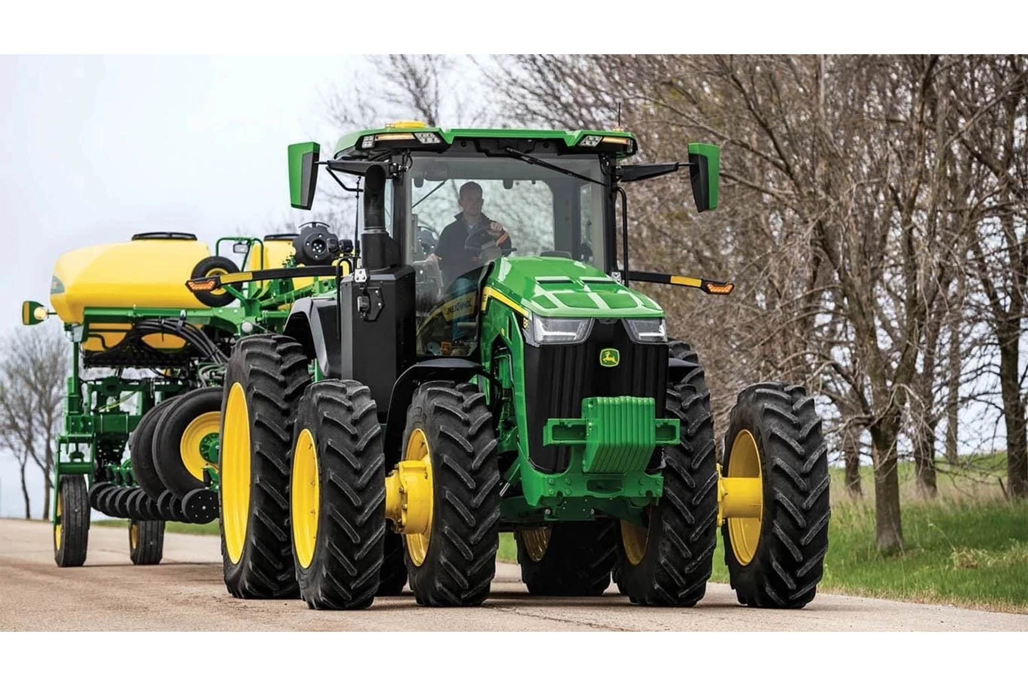 8R 340 Tractor being driven on a gravel road with a sprayer attachment