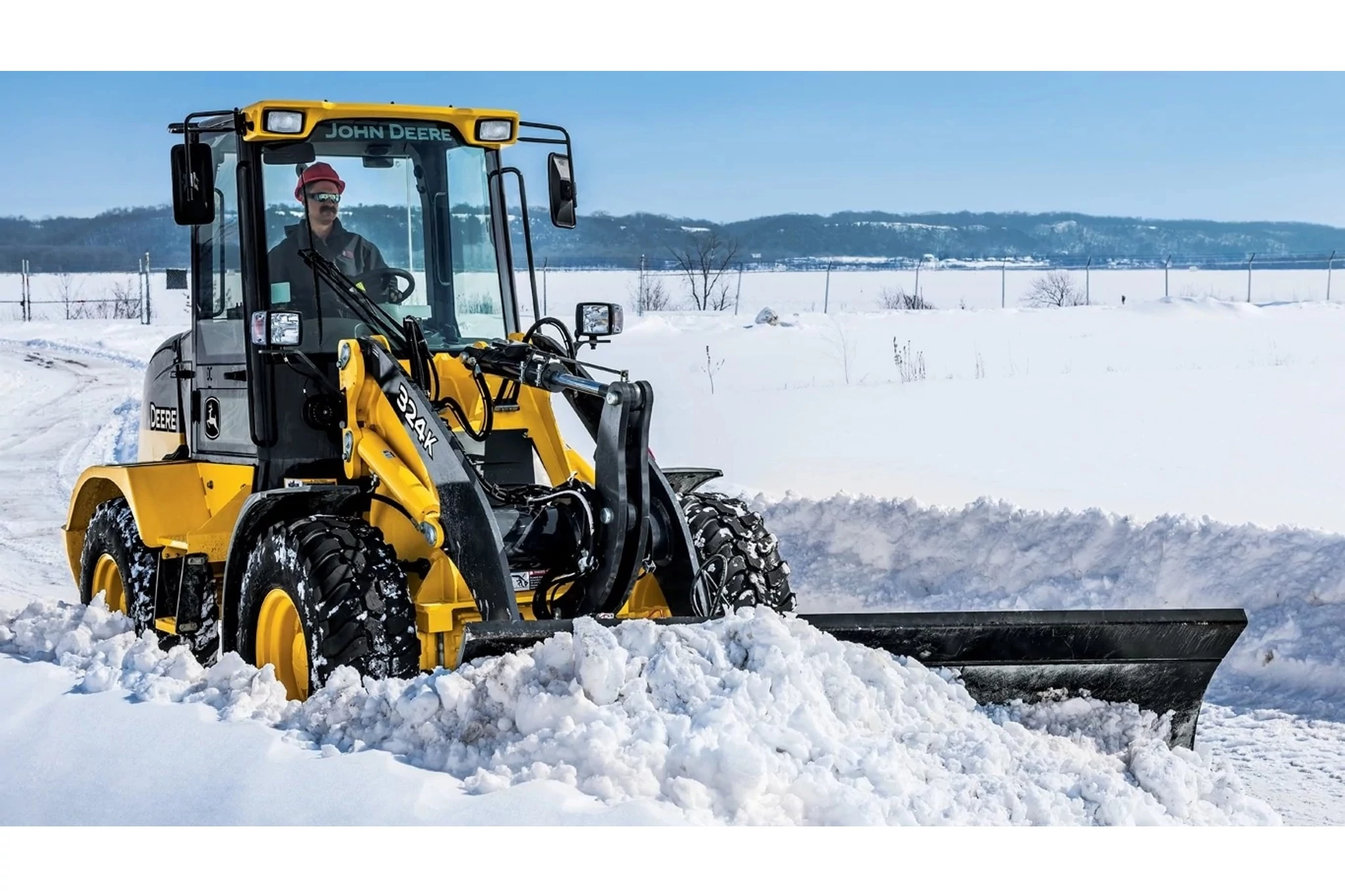 A 324K wheel loader with BL10B snow blade attachment plowing snow