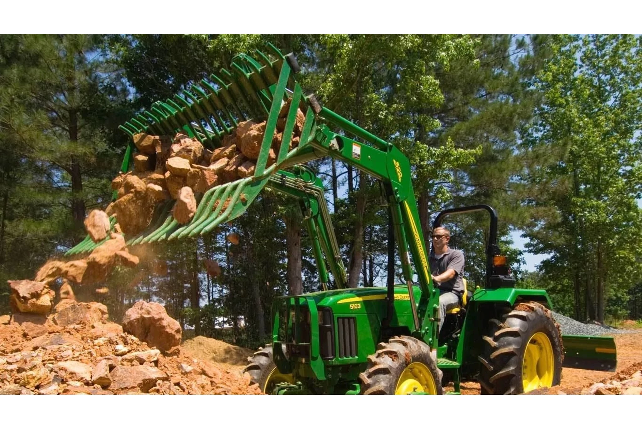 Frontier AR10 Rock Bucket attachment on a tractor dumping boulders