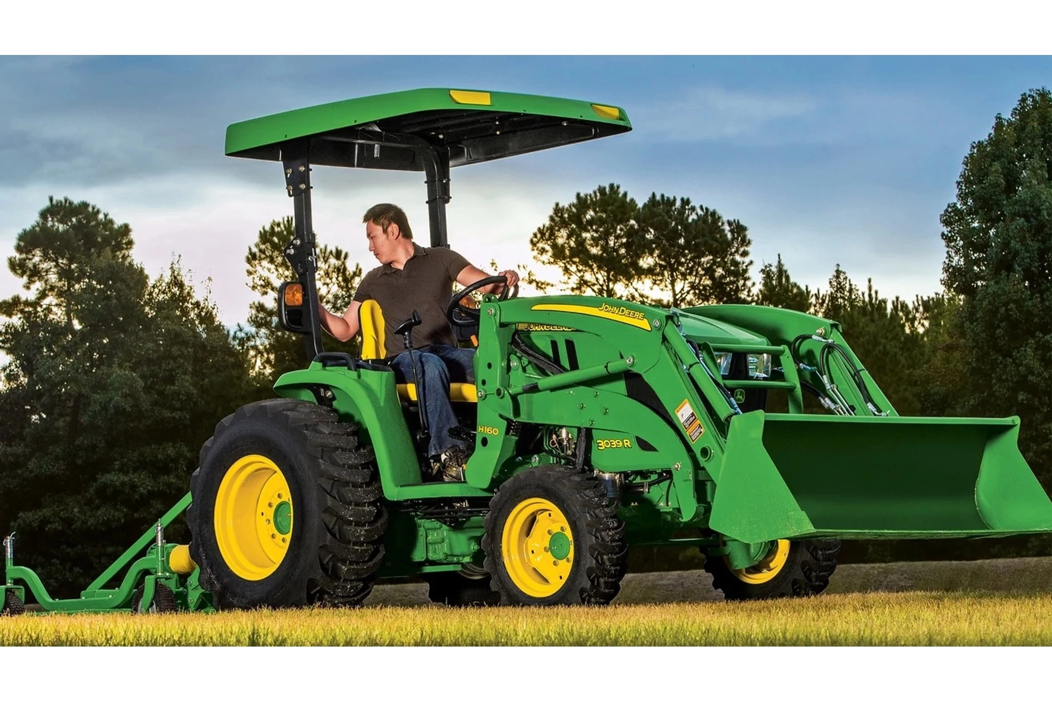 Front right view of a 3039R compact tractor equipped with a front-end loader, positioned in an open field