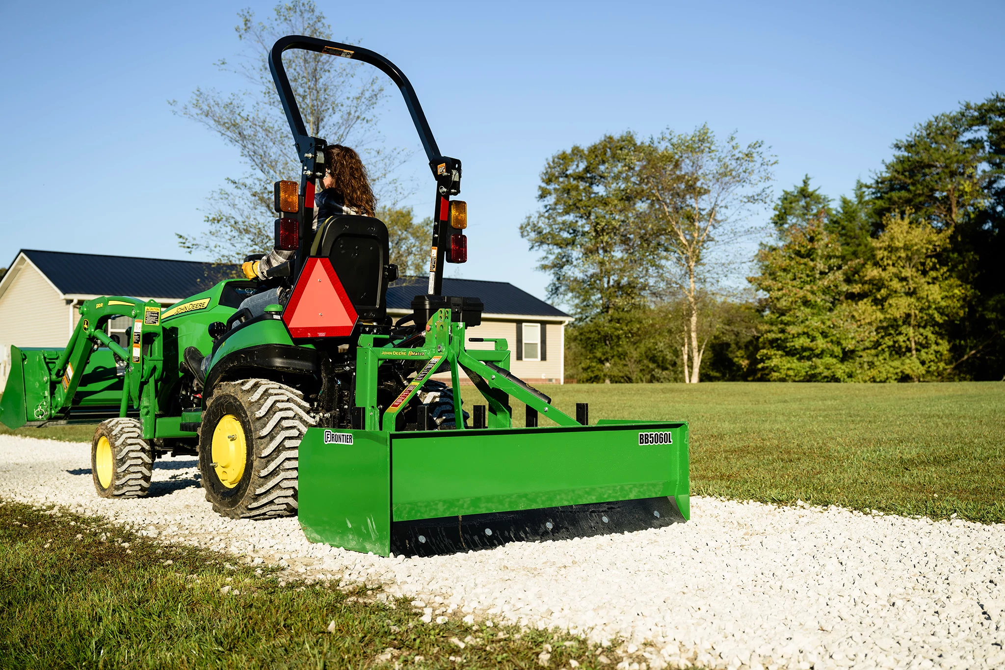 1025R Tractor with BB5060L Box Blade and AY11F Bucket on a gravel walk way