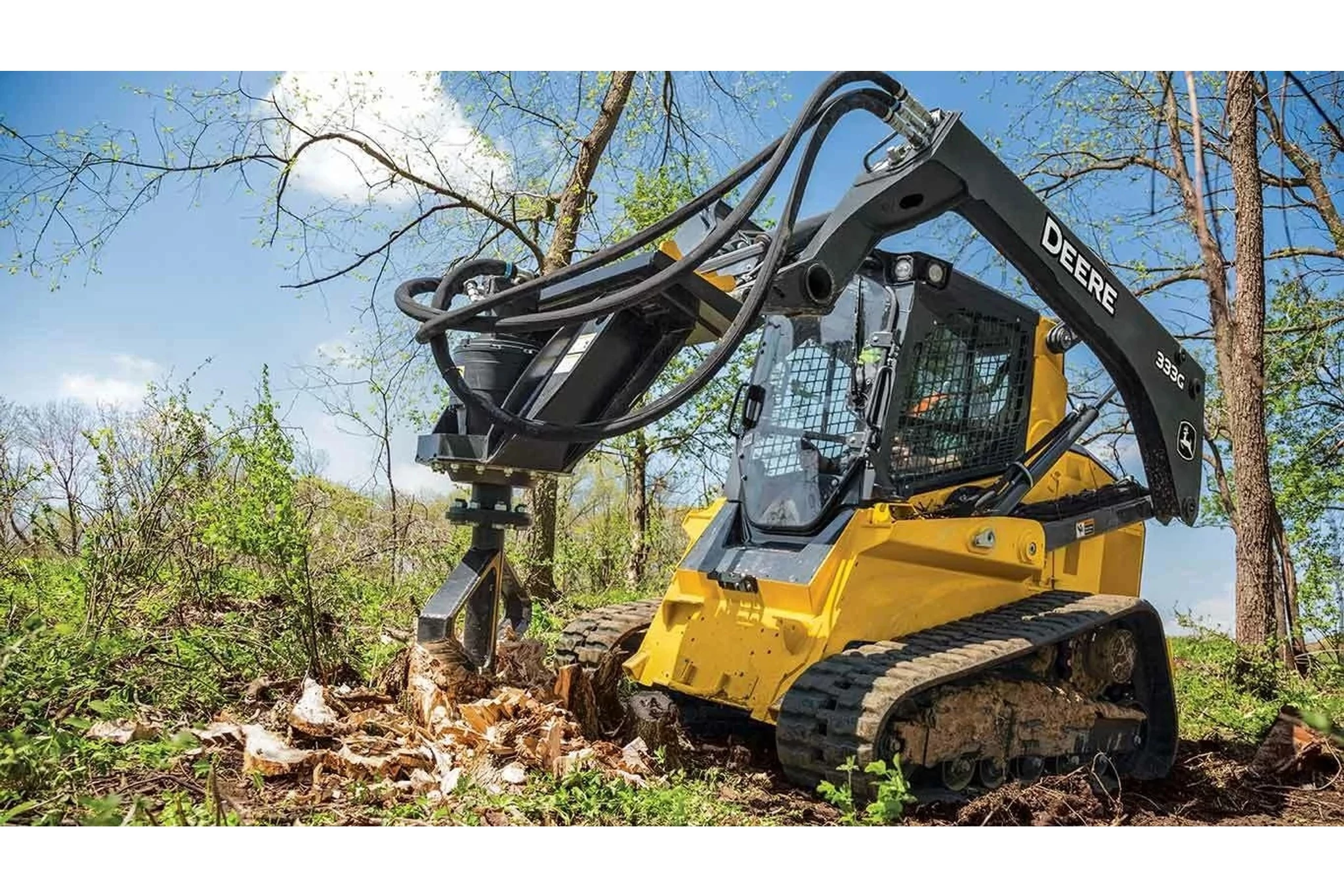 Front left view of 333G Compact Track Loader with SS30 Stump Shredder shredding a stump in a cleared field