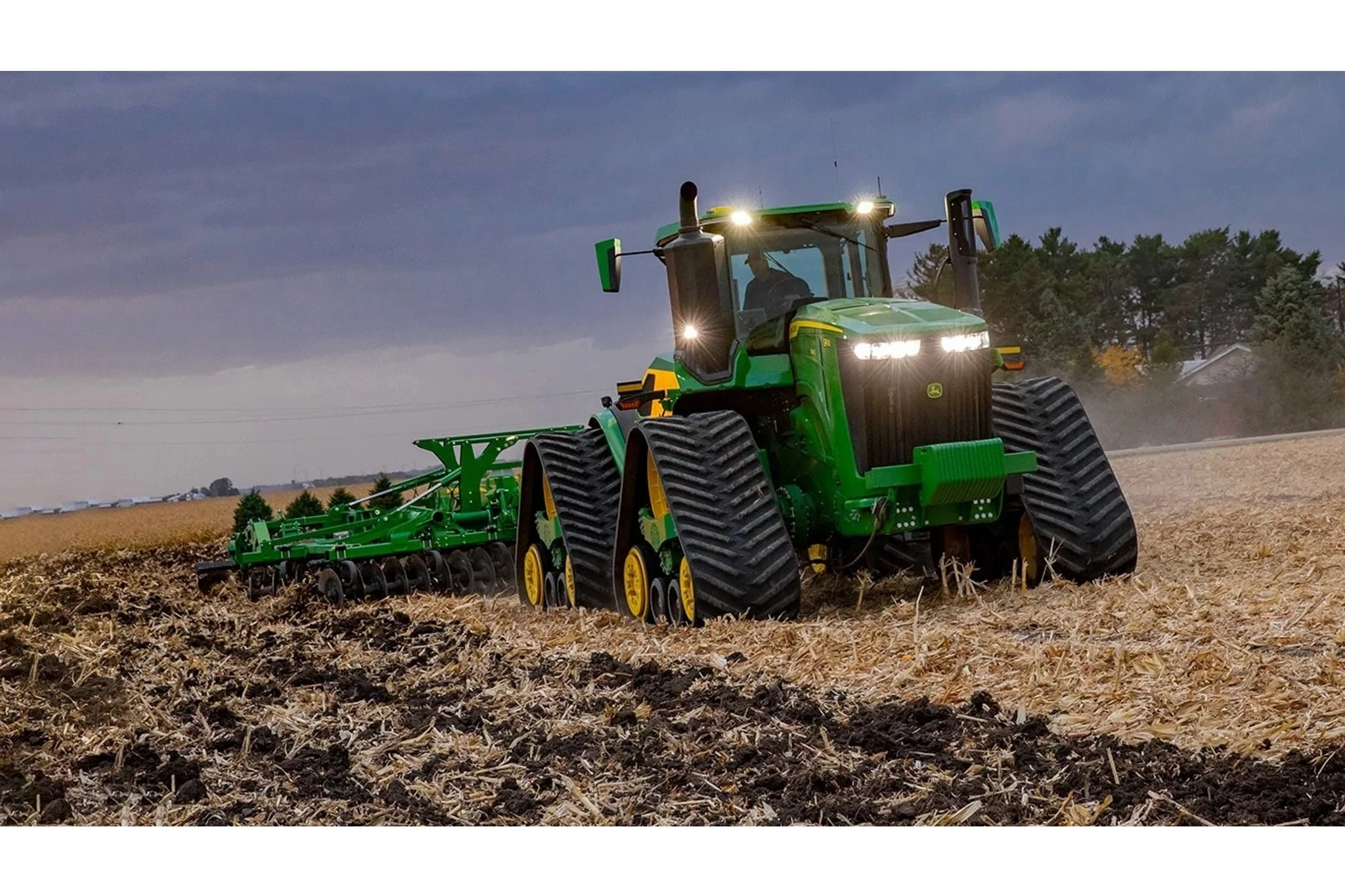 9RX 590 tractor at work in the field at dusk.